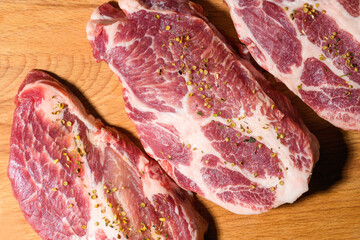 Sliced raw pork meat  with spices on wooden surface, top view