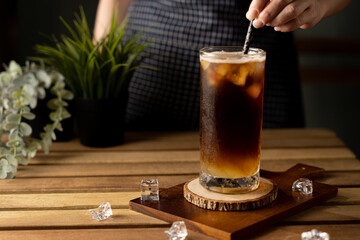Glass of espresso with lemon juice on wooden table and copy space, Summer Cocktail, Cold brew coffee or black tea. (close up, selective focus), Pouring cold drink.