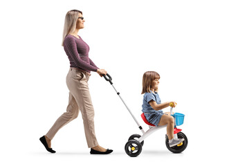 Mother pushing a daughter on a tricycle