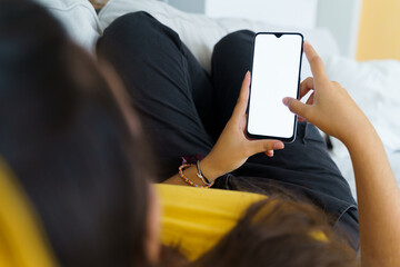 Unrecognizable young woman entertaining herself lying on the couch using the phone