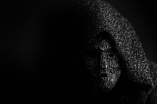 Portrait of a deamon in a dark mask on a black background with copy space