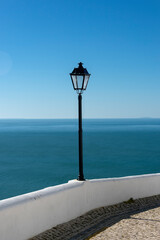 white wall and lamp post at viewing point at Sitio looking over Nazare, Portugal.