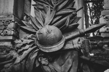 Grayscale closeup shot of the details of an old statue of helmet and war weapons