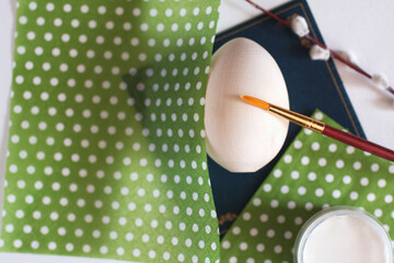 Wooden egg with a brush, glue, green napkins and willow, verba branch on dark background. Top view. Easter preparation concept background. Spring holidays gifts. Decoupage process, creativity, DIY