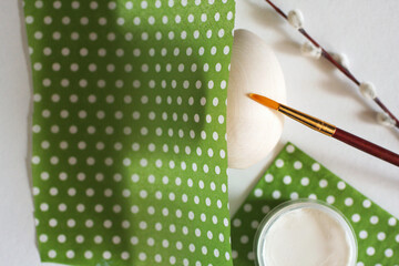 Wooden egg with a brush, glue, green napkins and willow, verba branch on white background. Top...