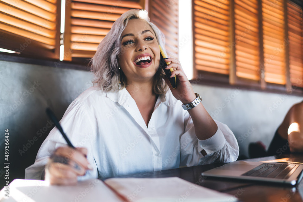 Poster cheerful female copywriter smiling while discussing creative ideas using cellphone application in co