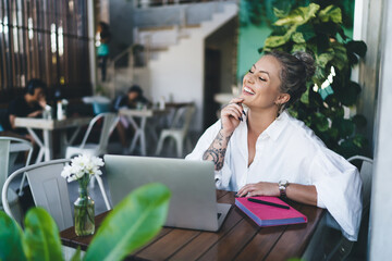 Happy IT professional with laptop computer working remotely at coworking terrace, successful female...