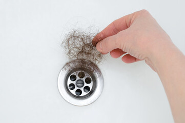 Drain hole in the bathroom. He takes out tuft of hair with his hand.