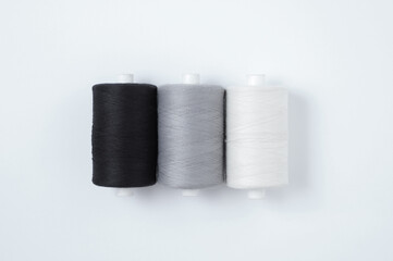Three spools sewing thread lying in a row. White background.