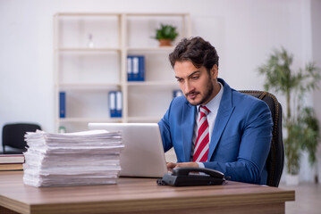 Obraz premium Young male employee and too much work in the office