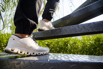 Closeup foot and sneakers of a woman step up on the metal spiral stairs