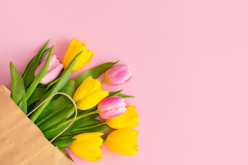 Bouquet of tulips in a paper bag on a pink background.