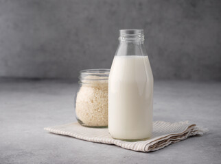 Vegan rice milk with rice grains on a gray concrete background. Copy space. Non dairy alternative...