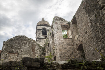Low angle shot of historical ruins and a church in Kotor Montenegro against clouds