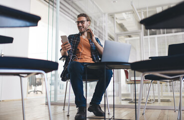Cheerful male copywriter searching information for new article using modern technology and...