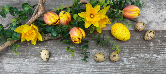Blumenarrangement mit Ostereiern auf Holzhintergrund.