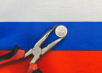 one Russian ruble coin in old pliers, the concept of the crisis in Russia and sanctions against the...
