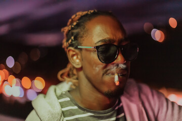 Afro Americans smoking a cigar, in the background city lights