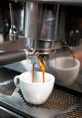 Creamy coffee pouring from a coffee machine up close