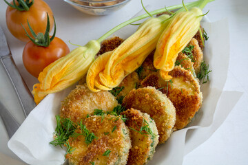 yummy vegetables on plate. Breaded fried zucchini pieces with tomatoes on white background 