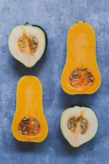 Four halves of cut squash with seeds on a blue grey background
