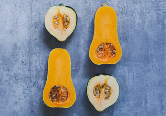 Four halves of cut squash with seeds on a blue grey background