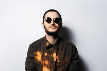 Fototapeta premium Portrait of young confident man wearing round sunglasses on white background.