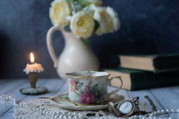 Vintage still life, a cup of tea, a clock, old books and other old things.