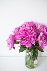 Beautiful bouquet of pink peony flowers in a vase on a white table. Flower surprise on March 8.