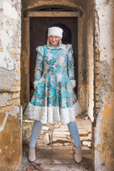 A beautiful woman in a winter coat and winter hat (Ushanka). A beautiful woman in an abandoned castle.