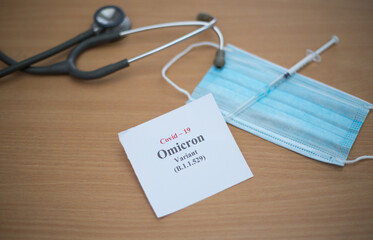 Medical facemask with a stethoscope and a syringe needle on the table - COVID Omicron variant