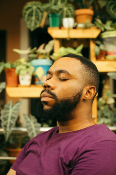 Portrait of a black gardener sitting in his plant in nursery in nigeria 