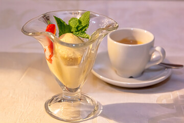 Vanilla ice cream with strawberries and mint is in a glass cup