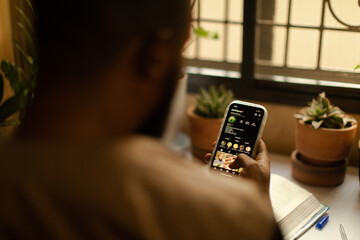 Portrait of a black gardener scrolling on his mobile phone at home