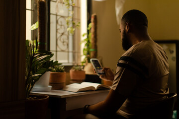 Portrait of a black gardener scrolling on his mobile phone at home