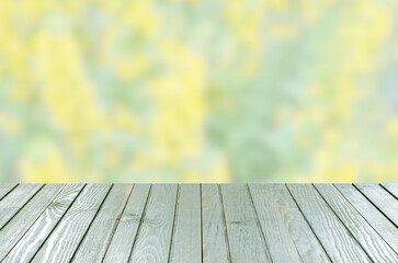 An empty wooden table. Blurry summer or spring background.