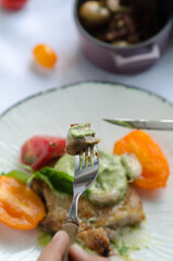 Pork fillet on the bone, with baked tomatoes and confit garlic. Food tasting in a restaurant