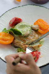 Pork fillet on the bone, with baked tomatoes and confit garlic. Food tasting in a restaurant