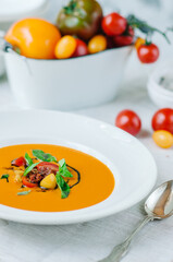 Delicious creamy tomato soup with herbs. Summer light yellow tomato soup.
