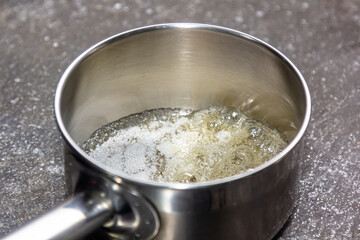 The cook cooks caramel from sugar in a saucepan