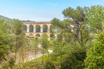 Obraz premium A partially obscured view towards the ancient two storey, Roman aqueduct on the outskirts of Tarragona on a spring day