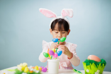 young girl making easter craft against plain background