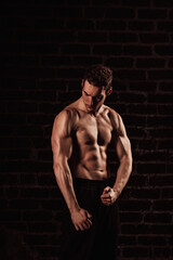 Naked torso of a young handsome man on a dark background