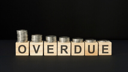 overdue - word of wooden blocks with letters on a black background. selective focus.
