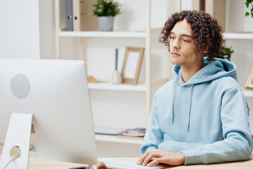 A young man sitting at a table in front of a computer freelance technologies