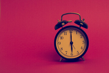 vintage old black alarm clock on pink background