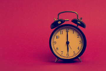 vintage old black alarm clock on pink background