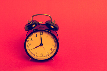 vintage old black alarm clock on pink background