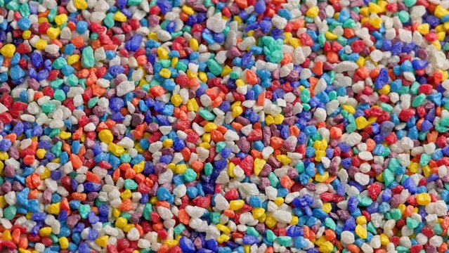 crushed colored stones on flat surface, slowly spinning, loopable closeup