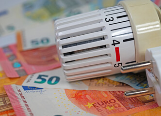 Thermostat vor Geldscheinen symbolisch für Heizkosten